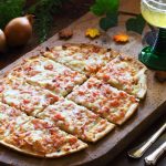 Tarte flambee dans une cuisine avec un verre de vin blanc